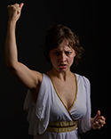 Antigone raises her right arm with a fist in defiance